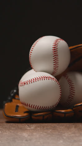 Vertical-Video-Close-Up-Studio-Baseball-Still-Life-With-Balls-And-Catchers-Mitt-On-Wooden-Floor-1